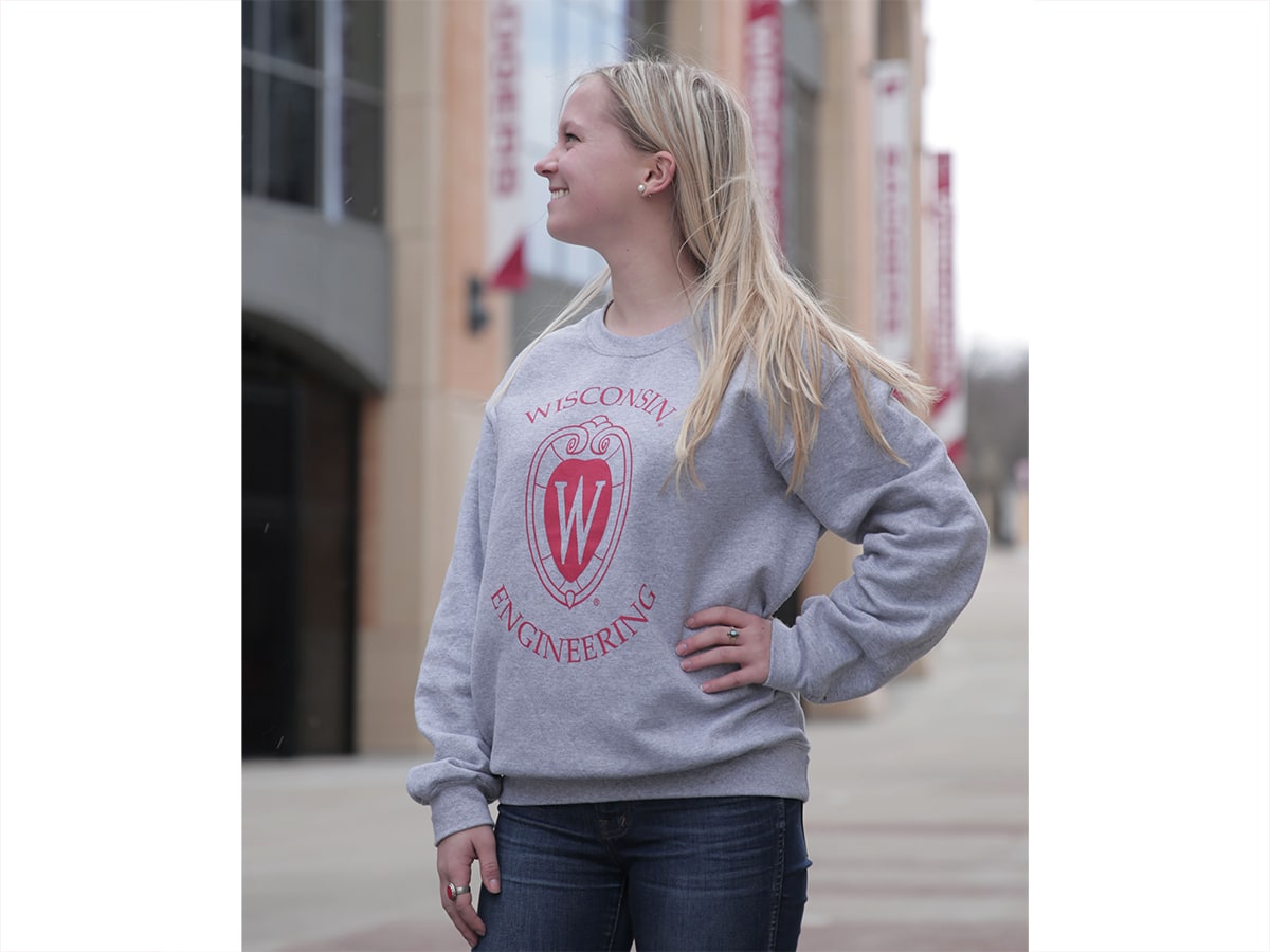 A female models the grey crew neck pullover with red College of Engineering crest and words Wisconsin Engineering.