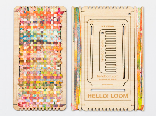 A small hand-held loom made of laser-cut wood covered with a colorful weaving.