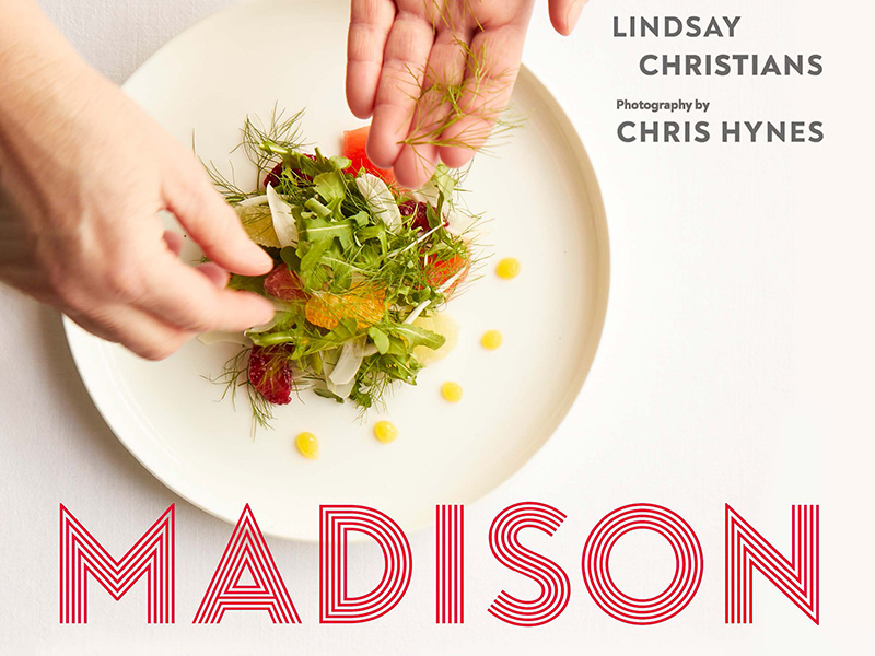 A crop of the cover of the new cookbook Madison Chefs, showing a chef's hands putting the finishing touches on a plated meal.
