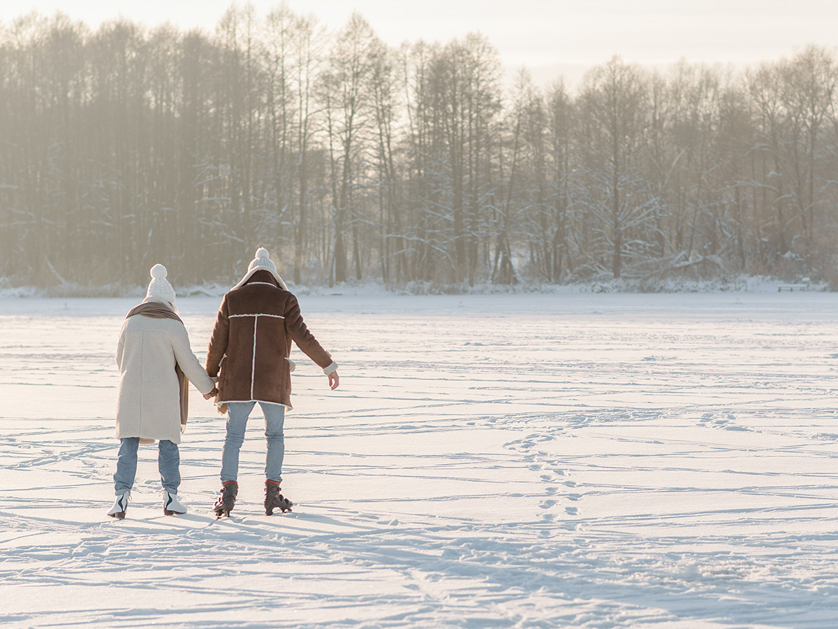 Two people ice skate on a frozen lake.