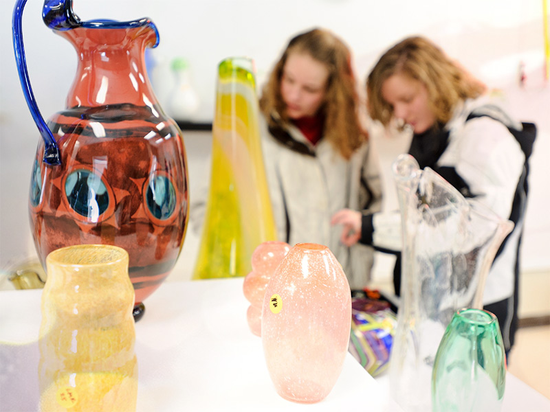Colorful handblown glass is displayed while shoppers browse.