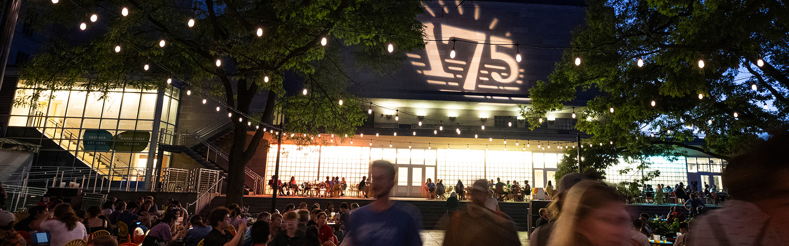 People on the Memorial Union Terrace with "175" projected on the side of a building behind them